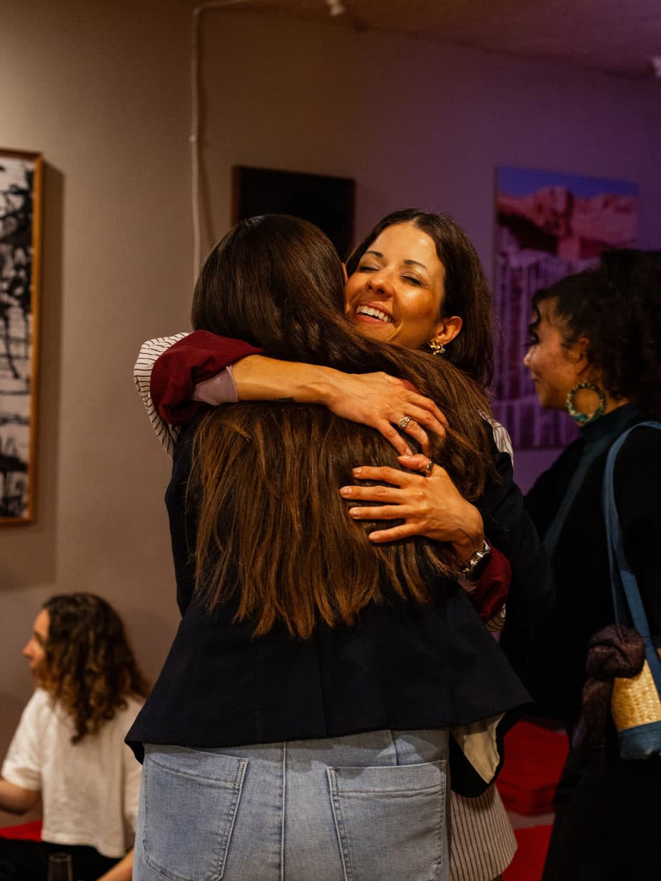 Two women hugging after the stories, one of them smiling over the other's shoulder.