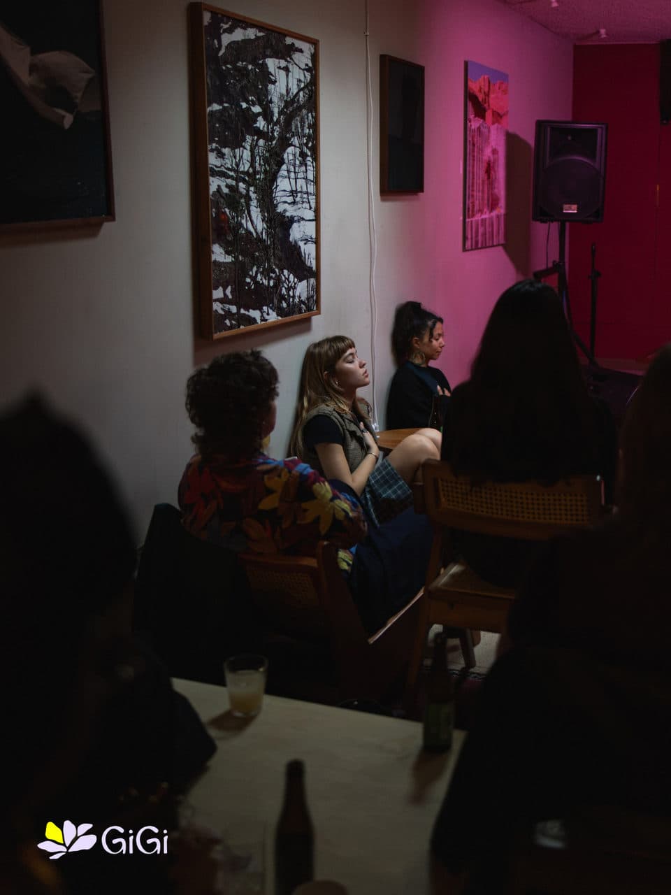 The room in low light at the start of the evening, women settling in before the first story.